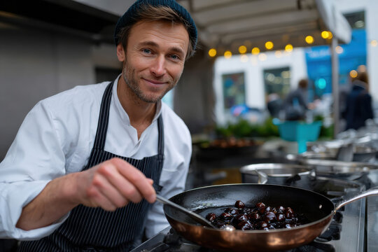 A cheerful chef prepares chestnuts in a frying pan at an outdoor market, conveying warmth and community spirit during a festive culinary experience.