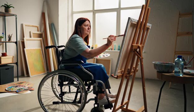 Creative disabled woman painting in a wheelchair, symbolizing inclusion and empowerment. International Day of Persons with Disabilities concept.
