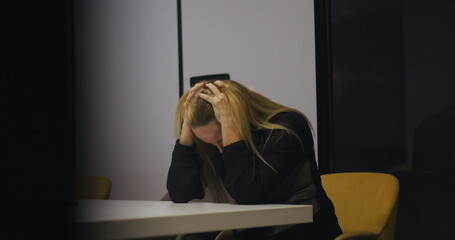 Exhausted middle-aged professional covers ears and closes eyes in moment of visible distress during...