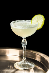 Elegant margarita cocktail in a crystal coupe glass with salt rim and fresh lime slice, isolated on black background, perfect for bar menus, beverage branding, cocktail advertising