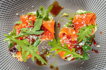 Fresh salmon bruschetta with avocado spread, arugula and parmesan flakes, ideal for restaurant menus, healthy food promotions and modern culinary branding