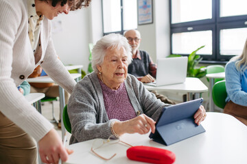 Elderly woman learning digital skills with tutor help.
