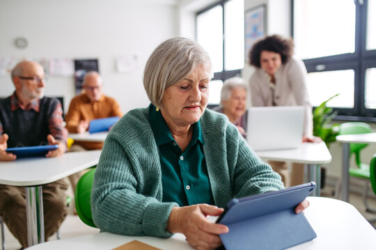 Elderly woman learning digital skills with tutor help.