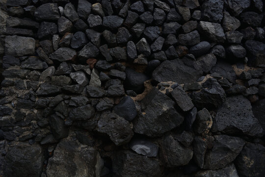 Dark, rough and elegant rock texture surface closeup. Black abstract rustic nature pattern for horizontal background or backdrop.
