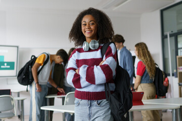 Confident teen student standing in modern classroom.