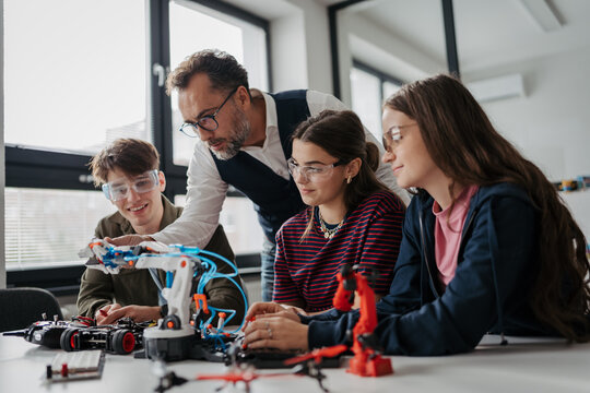 High school students working on robotics project with their teacher.