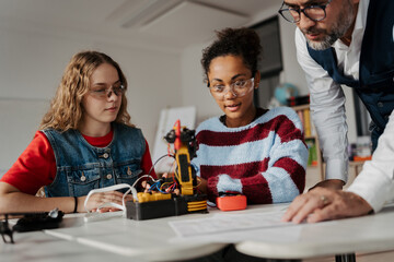 High school students working on robotics project with their teacher.
