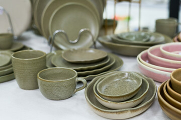 Ceramic tableware set featuring plates, bowls, cups, and saucers arranged on surface, showcasing variety of shapes and sizes with neutral and pastel tones, no people visible