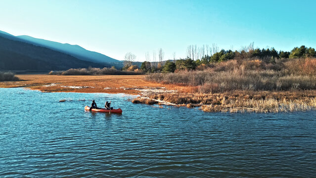 Two individuals paddle a canoe on a serene river, surrounded by autumnal landscapes. The scene captures a peaceful weekend activity, emphasizing connection with nature and an active lifestyle. - Powered by Adobe