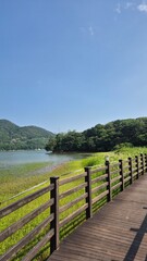Lakeside wooden deck overlooking calm water and distant mountains under a bright clear sky.