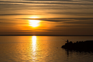 Silhouette of a lonely fisherman at sunset on a pier in Ravda, Burgas, Bulgaria 