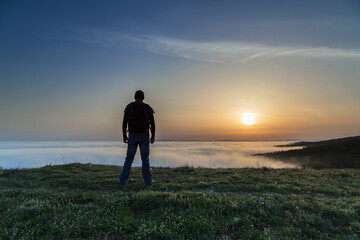 Back view of man on the hill over the fog at sunset. Sofia, Bulgaria