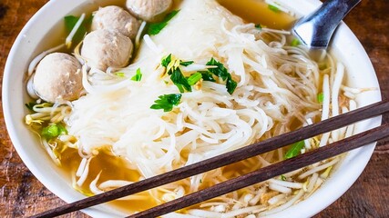 Delicious vietnamese pho noodle soup with meatballs and herbs