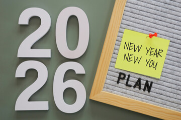 white number of New Year 2026 with word "plan" and post-it paper with text "new year new you" pin on letter board, symbolizing fresh goals, motivation, and starts new year personal fresh planning.
