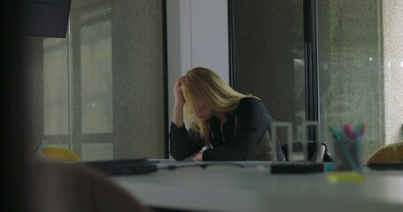 Frustrated businesswoman slams hand on conference table in anger, overwhelmed during workplace crisis, head bowed with hair falling forward, surrounded by scattered items
