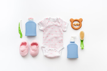 Set of baby hygiene cosmetic products - shampoo and soap with a comb. Eco friendly accessories - bodysuit and wooden toys with bottle of milk on white background, top view
