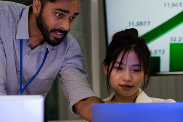 Business team analyzing data on laptops with growth chart in background. Diverse professionals collaborating in office, discussing financial performance, strategy, and success analytics in  workplace.