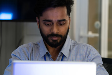 Business team analyzing data on laptops with growth chart in background. Diverse professionals collaborating in office, discussing financial performance, strategy, and success analytics in workplace.