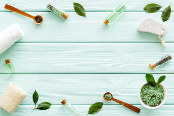 Fototapeta na wymiar Organic cosmetics products - tea tree essential oil and sea salt near green leaves top view