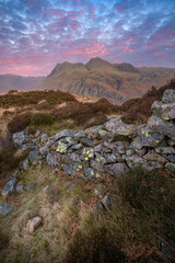 Great Langdale sunrise with old stone wall and stunning mountains seen from Side Pike, Lake District, UK.