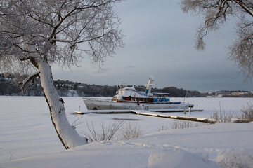 An old boat moored on a frozen lake on a winter day