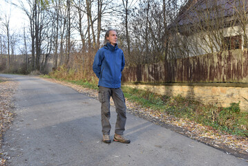 Obraz premium Man standing on an autumn road in blue jacket