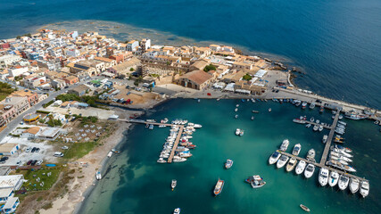 Fototapeta premium Aerial view of the marina of the town of Marzamemi, in the province of Syracuse, Sicily, Italy. It is a coastal village overlooking the crystalline waters of the Mediterranean Sea. Sunny summer day.