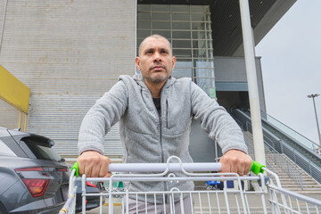 Man pushing shopping cart in a parking lot, shopping completed after visiting the supermarket