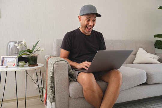 Man laughing excitedly while working remotely from home on a laptop - Powered by Adobe