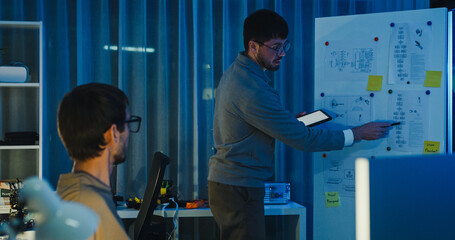 Team adult male engineer develop present AI robotics hand project at tech workspace night....