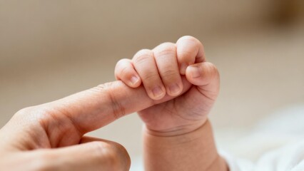 Baby's hand grasping adult's finger, symbol of love and connection