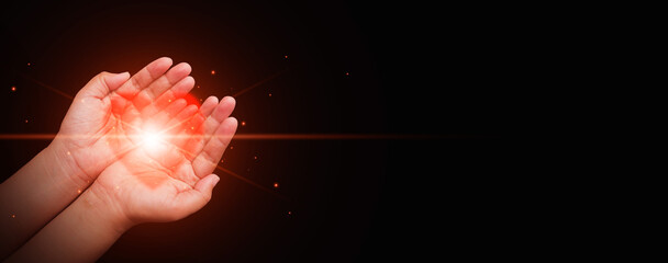 Hands gently holding a glowing red heart against a dark background, Health care, CSR, insurance, family, World Heart Day, World Health Day, love, rescue, wellbeing, hope, support, and compassion