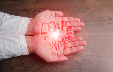 Hands gently holding a glowing red heart-shaped love and care text. Health care, CSR, insurance, family, World Heart Day, World Health Day, love, rescue, wellbeing, hope, support, and compassion