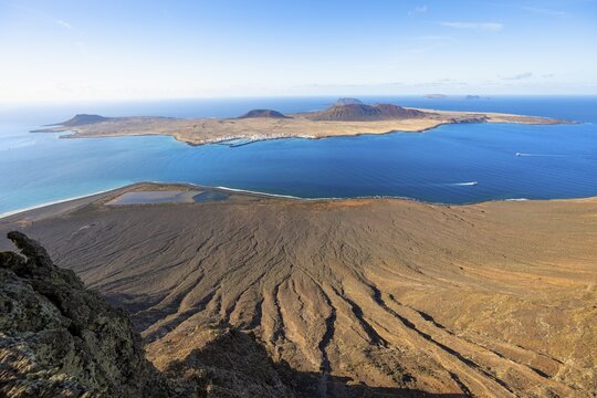 View of steep cliffs by the sea and island of La Graciosa with volcanic craters in the evening light, Mirador del R&iacute;o viewpoint designed by artist C&eacute;sar Manrique, Lanzarote, Canary Islands, Spain