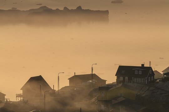 Inuit settlement in front of icebergs in the fog, midnight sun, summer, Ilulissat, Ilulissat Icefjord, Disko Bay, West Greenland, Greenland