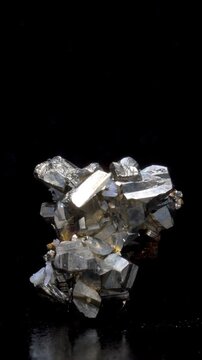 Iron Pyrite (iron sulphide: FeS2) or 'Fool's Gold' (from Bulgaria) with quartz and chalcopyrite crystals, rotating slowly against a black background. Vertical.