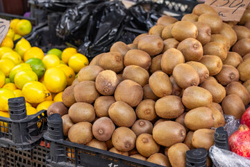 Display of ripe kiwis at the farmers' market. Many kiwis are sold at the store. Vegetarian and healthy food. Farmers' market with fresh fruits and vegetables.