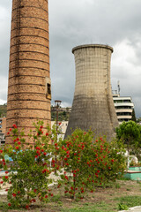 Obraz premium Kühlturm und Ziegelschornstein mit Blüten in Kuçovë, Kuçovë, Bezirk Berat, Albanien