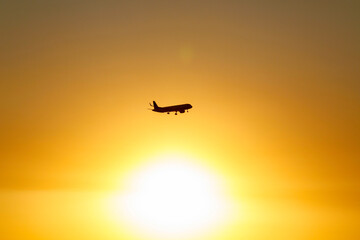 A commercial aircraft captured mid-flight against a glowing sun and warm sky, symbolizing departure, hope, and global mobility.