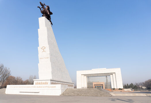 View of Ala-Too Square showing Manas monument on tall white pedestal left and National History Museum right, empty paved plaza. Bishkek, Kyrgyzstan.
