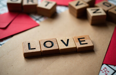 Wooden letter tiles spelling LOVE arranged on kraft paper with red envelopes