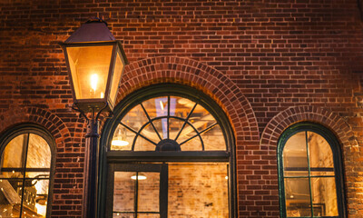 Fototapeta premium Vintage street lantern glowing against historic brick architecture in the Distillery District of Toronto, Canada, captured during the evening.
