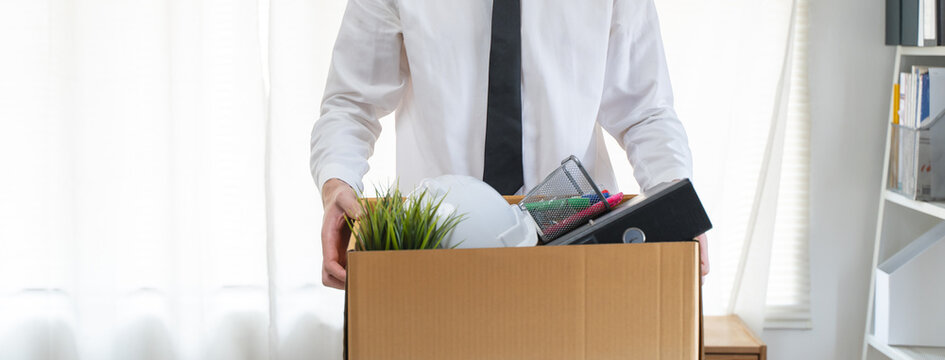 lay off workers. Banner size closes up hands of usinessman holding box of stuff to leave office after fired from work.