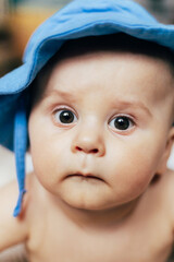 A baby lying on their stomach on a soft blanket reaches for colorful toys in a play area. Warm natural light and a cozy home environment create a bright and engaging family moment.