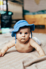 A baby lying on their stomach on a soft blanket reaches for colorful toys in a play area. Warm natural light and a cozy home environment create a bright and engaging family moment.