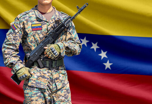 Venezuela flag with soldier in military uniform holding assault rifle in front of it