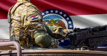 Missouri US state flag with soldier at machine gun turret in front of it.