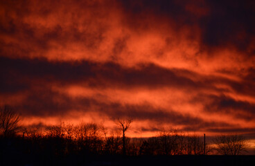 dark photo of sunset with fiery reflection of the sun on the clouds