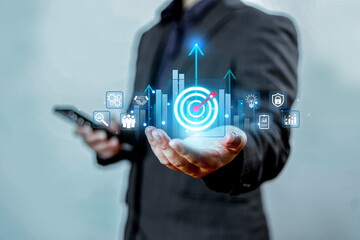 Businessman presenting digital target icon with rising bar charts and analytics symbols, representing strategy, growth planning, innovation, and future business performance improvement.