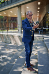 Mature man checking mobile phone on city steps